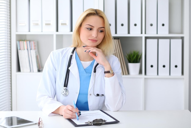 Femme médecin remplissant un formulaire médical assis au bureau. Concept de médecine et de soins de santé.