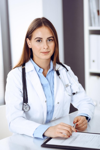 Femme médecin remplissant un formulaire médical assis au bureau du bureau de l'hôpital. Médecin au travail. Concept de médecine et de soins de santé.