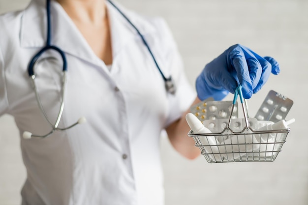 Une femme médecin sans visage tient un mini panier avec des médicaments