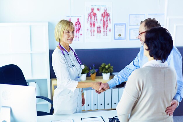 Femme médecin serrant la main d'un patient et souriant