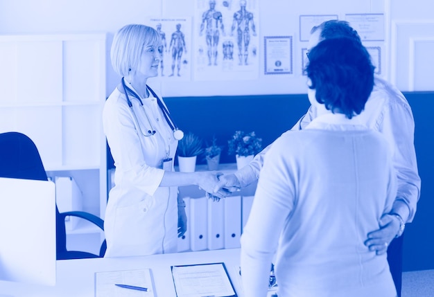 Photo femme médecin serrant la main d'un patient et souriant