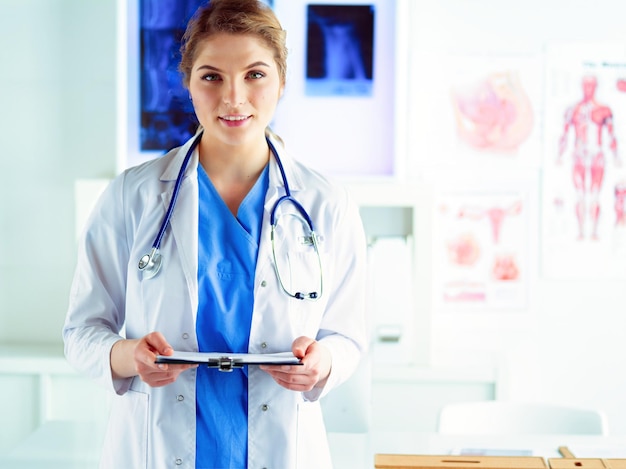 Femme médecin souriante avec un dossier en uniforme debout