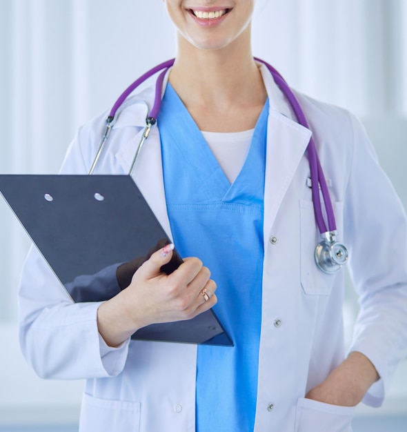 Femme médecin souriante avec un dossier en uniforme debout
