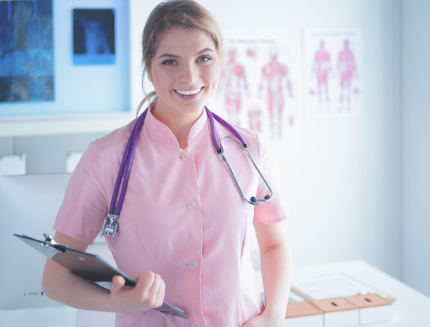 Femme médecin souriante avec un dossier en uniforme debout