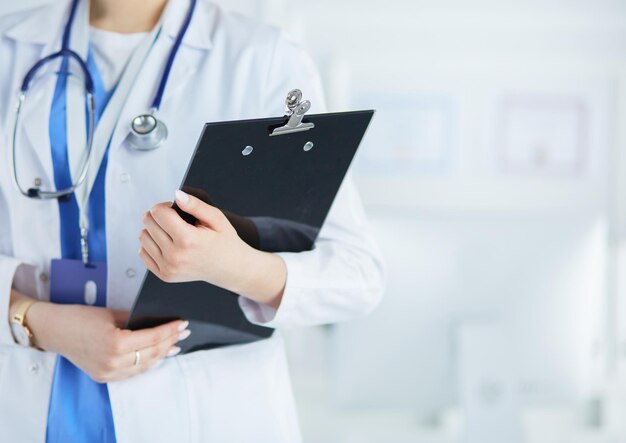 Femme médecin souriante avec un dossier en uniforme debout