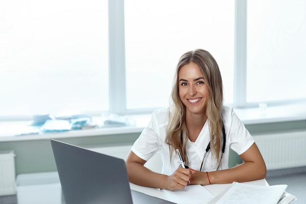 Une femme médecin souriante est assise au bureau