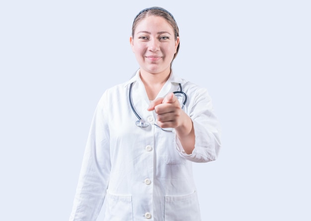 Femme médecin souriante, pointant vers la caméra Femme médecin heureuse, pointant vers vous Jeune médecin, pointant vers vous