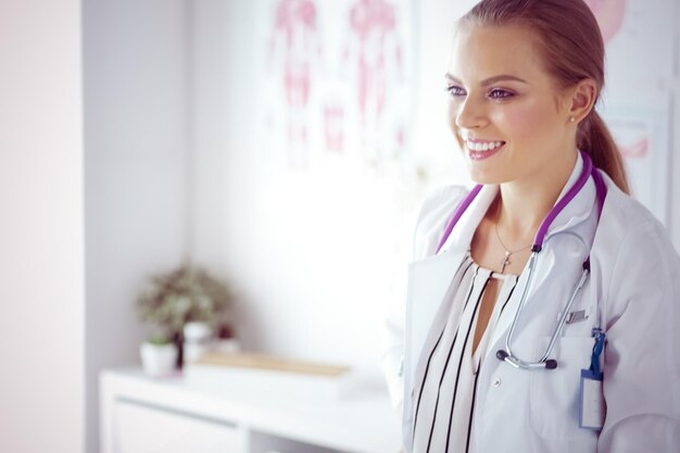 Femme médecin souriante avec un stéthoscope médical en uniforme debout