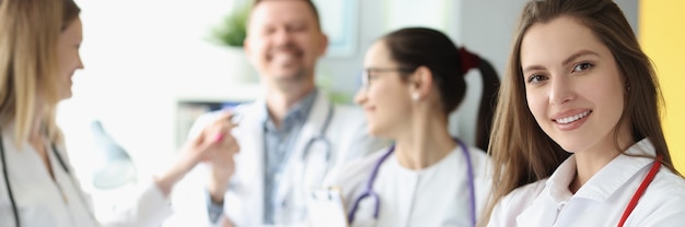 Femme médecin souriante avec stéthoscope rouge debout sur fond de collègues