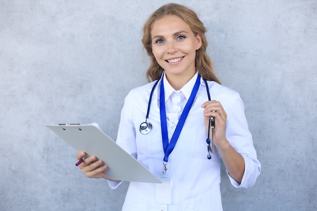 Femme médecin souriante avec stéthoscope tenant une carte de santé isolée sur fond gris.