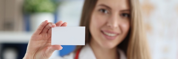 Photo femme médecin souriante tenant une carte de visite blanche