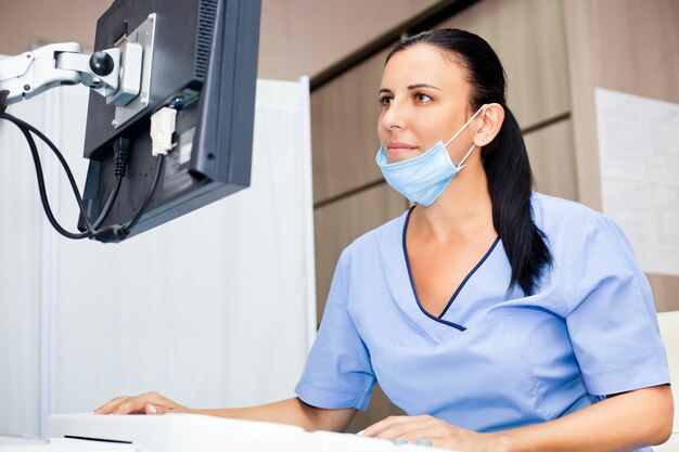 Femme médecin souriante en uniforme médical bleu et masque