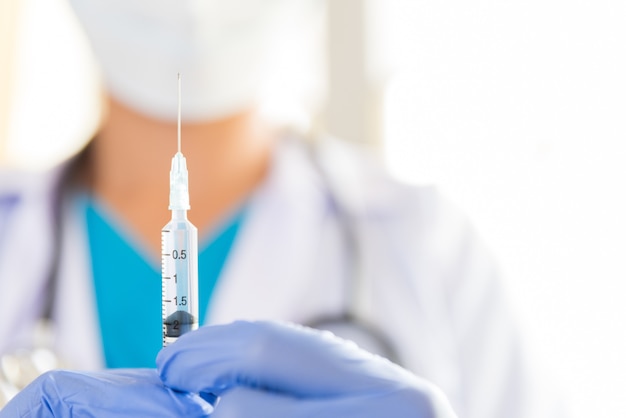 Femme médecin avec un stéthoscope sur l&#39;épaule tenant la seringue et le vaccin.