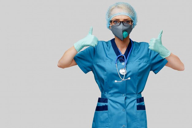 Femme médecin avec stéthoscope portant un masque de protection et des gants en latex sur un mur gris clair
