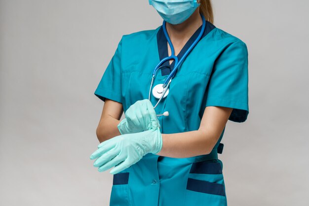 Femme médecin avec stéthoscope portant un masque de protection et des gants en latex