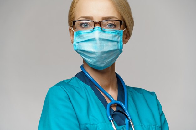 Femme médecin avec stéthoscope portant un masque de protection et des gants en latex