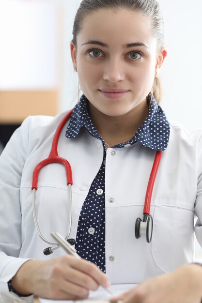 Femme médecin avec stéthoscope remplit un document