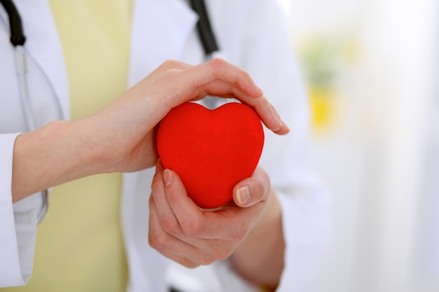 Femme médecin avec stéthoscope tenant le coeur. Couple de patients assis en arrière-plan