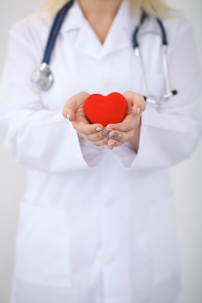 Femme médecin avec stéthoscope tenant le coeur. Couple de patients assis en arrière-plan