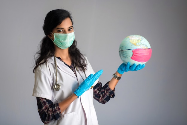 Femme médecin tenant un globe terrestre avec un masque de médecine. Épidémie mondiale de concept de coronavirus.