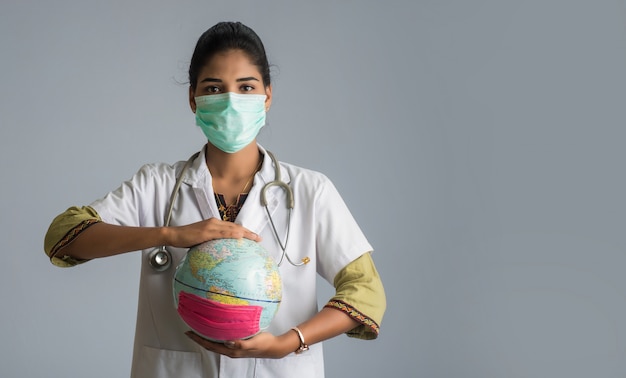 Femme médecin tenant un globe terrestre avec un masque de médecine. Épidémie mondiale de concept de coronavirus.