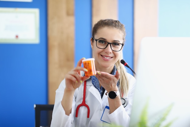 Femme médecin tenant un pot de capsules dans sa clinique des mains