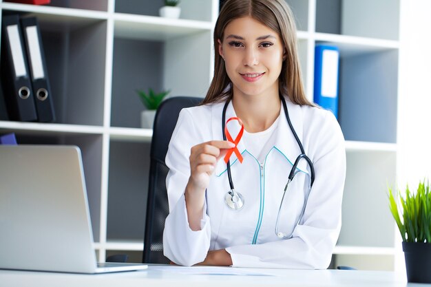 Femme médecin tenant un ruban rouge comme symbole du sida.