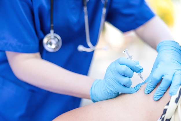 Une femme médecin tenant une seringue fait une injection au patient dans des vaccins médicaux