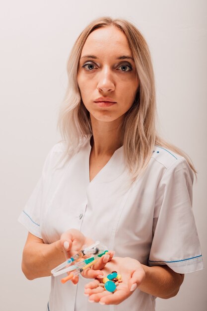 Femme médecin tenant des seringues avec vaccin et pilules dans les mains
