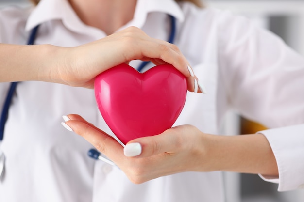 Femme médecin tenir dans les bras et couvrir jouet rouge