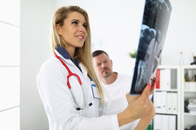 Femme médecin tient une radiographie à côté du patient assis