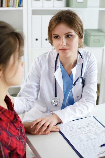 Femme médecin touchant l'épaule du patient pour l'encouragement, l'empathie, les acclamations et le soutien après un examen médical