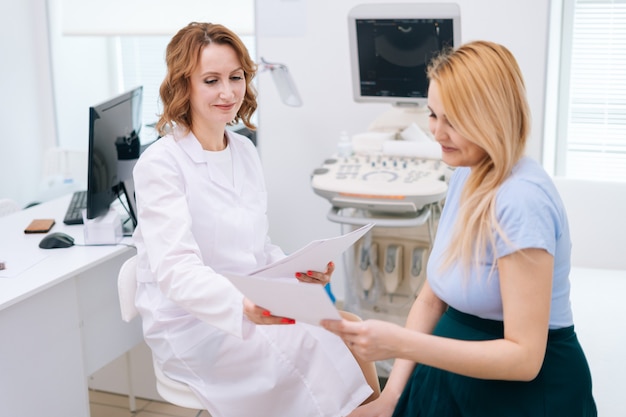 Une femme médecin transmet les résultats de l'échographie à une jeune femme enceinte