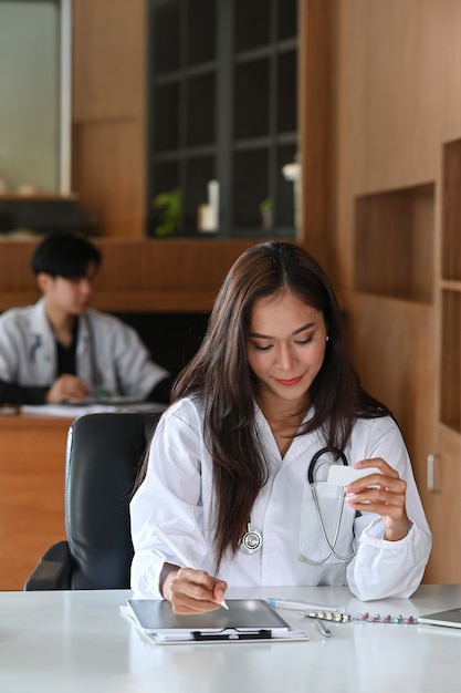 Femme médecin en uniforme blanc travaillant au bureau de la clinique médicale.