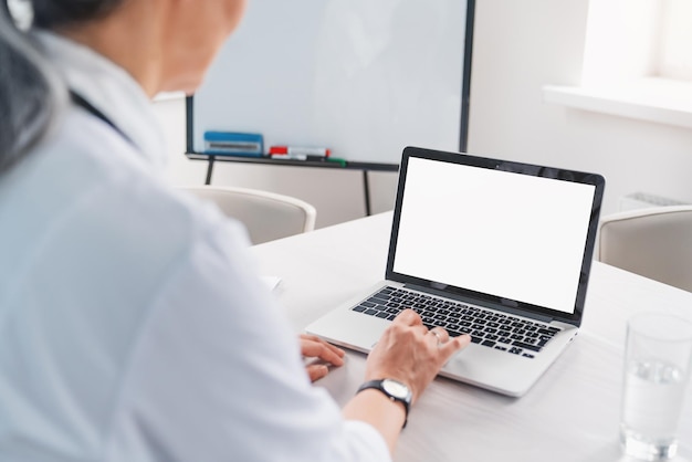 Femme médecin utilisant un ordinateur portable avec maquette à l'écran pour le travail médical au bureau de l'hôpital moderne