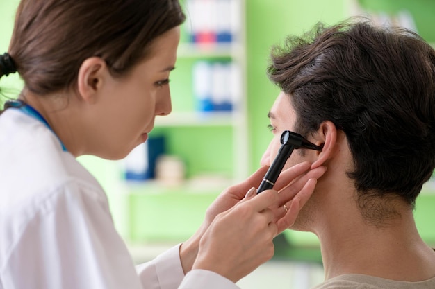 Femme médecin vérifiant l'oreille du patient lors d'un examen médical