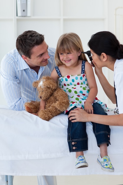 Femme médecin vérifiant les oreilles de la jeune fille souriante