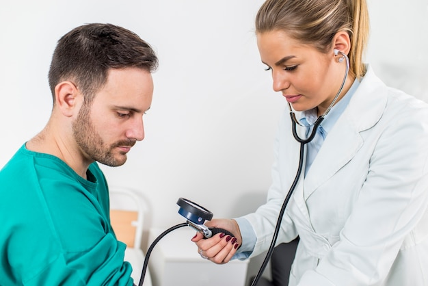 Photo femme médecin vérifiant la pression artérielle d'un patient à la clinique