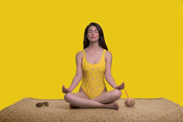 femme méditant sur un tapis de palmier sur fond jaune concept de vacances d'été