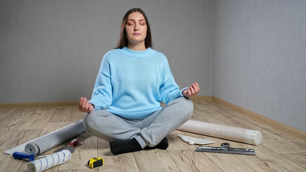 Une femme médite assise sur du parquet parmi les matériaux de construction