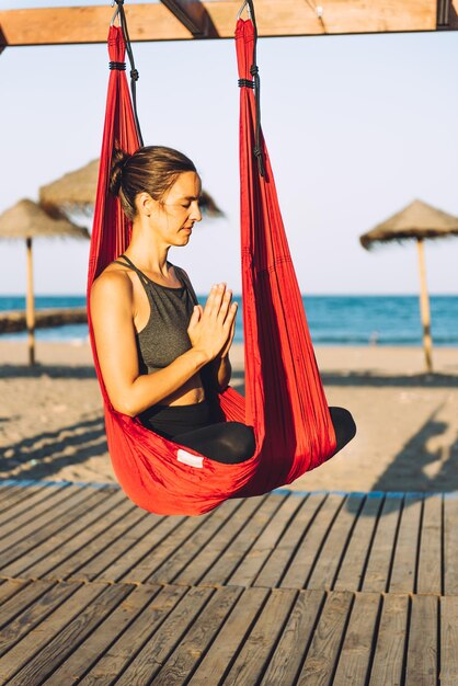 Une femme médite assise sur de la soie sur la plage.