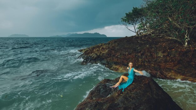 Femme médite se détend sur une colline de récif rocheux sous la pluie orageuse du matin mer nuageuse