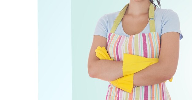 Femme de ménage debout avec les bras croisés portant un tablier et des gants en caoutchouc