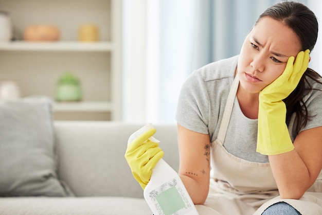 Femme de ménage et femme fatiguées de nettoyer le comptoir et la table des meubles dans le salon de l'appartement Travail ménager épuisé et frustré avec un vaporisateur pour nettoyer avec des produits dans les mains