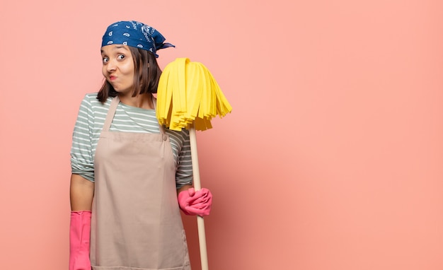 Photo femme de ménage jeune femme haussant les épaules, se sentant confus et incertain, doutant des bras croisés et regard perplexe