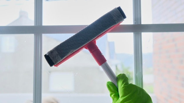 Photo femme de ménage nettoyant les vitres avec un nettoyant pour vitres