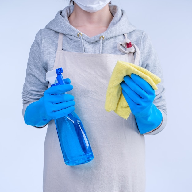 Femme de ménage en tablier faisant le nettoyage avec nettoyant pour bouteille