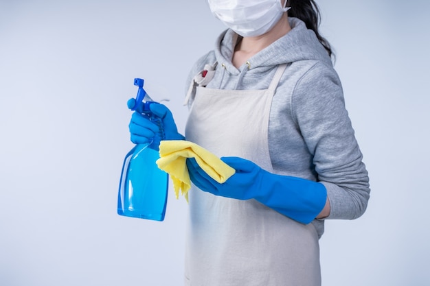 Femme de ménage en tablier faisant le nettoyage avec nettoyant pour bouteille
