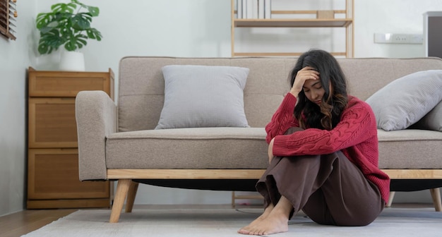 Une femme mentale malheureuse et solitaire déprimée, assise seule sur le canapé à la maison, la main sur le visage, ressent du stress, une déception triste et inquiète face à un problème pendant une pandémie de coronavirus ou de covid19