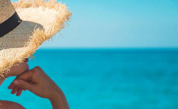 Femme à la mer dans un chapeau. Mise au point sélective. Voyager.